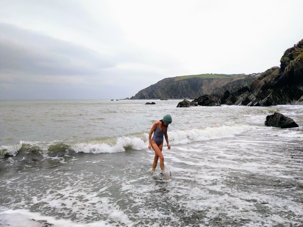 A woman cold water swimming on a beach in Devon
